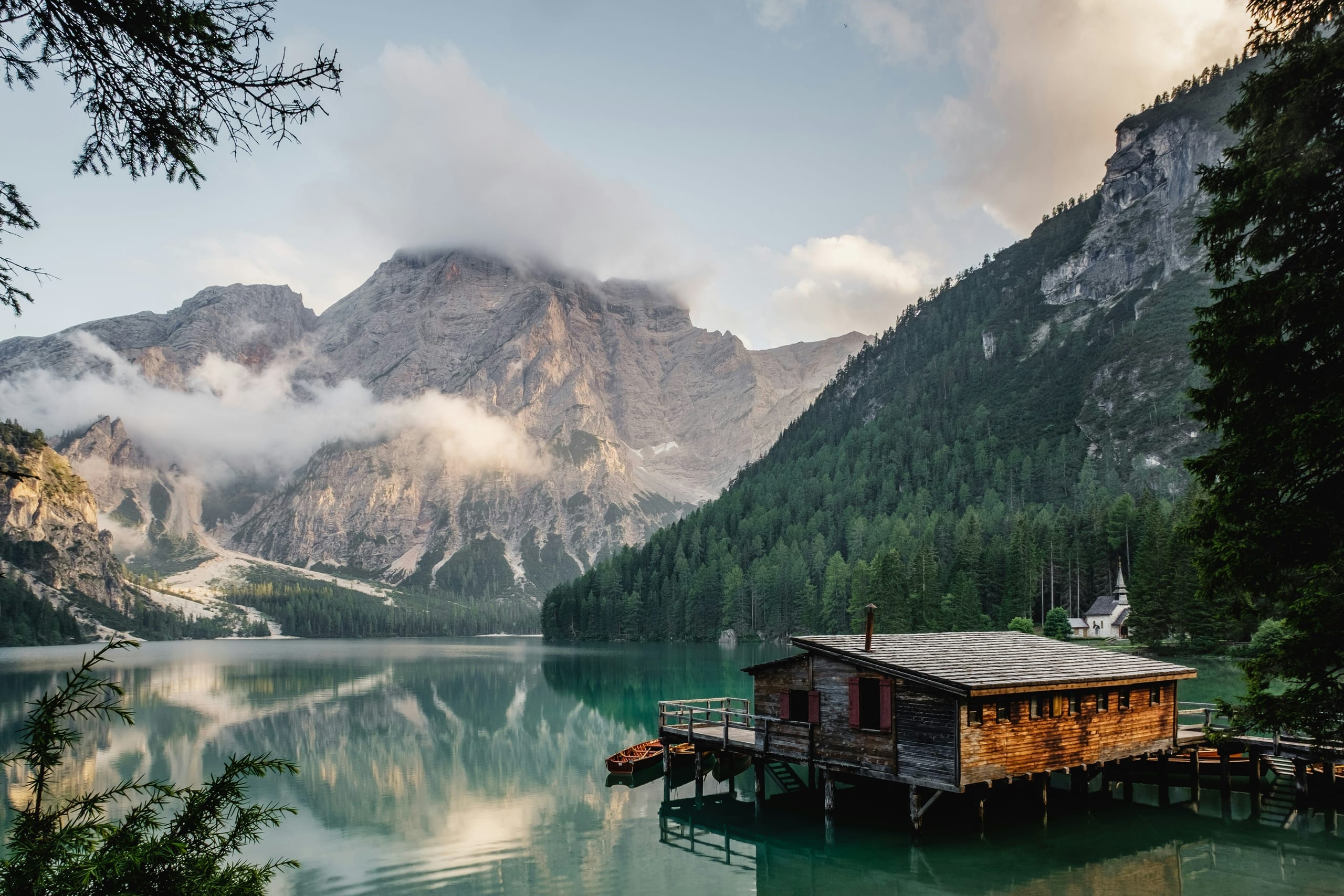 A lakeside cabin beneath misty mountain peaks